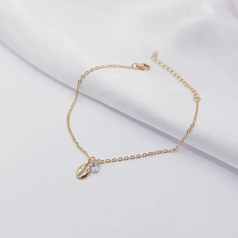 PULSEIRA DOURADA COM PINGENTE BÚZIOS E PONTO DE LUZ