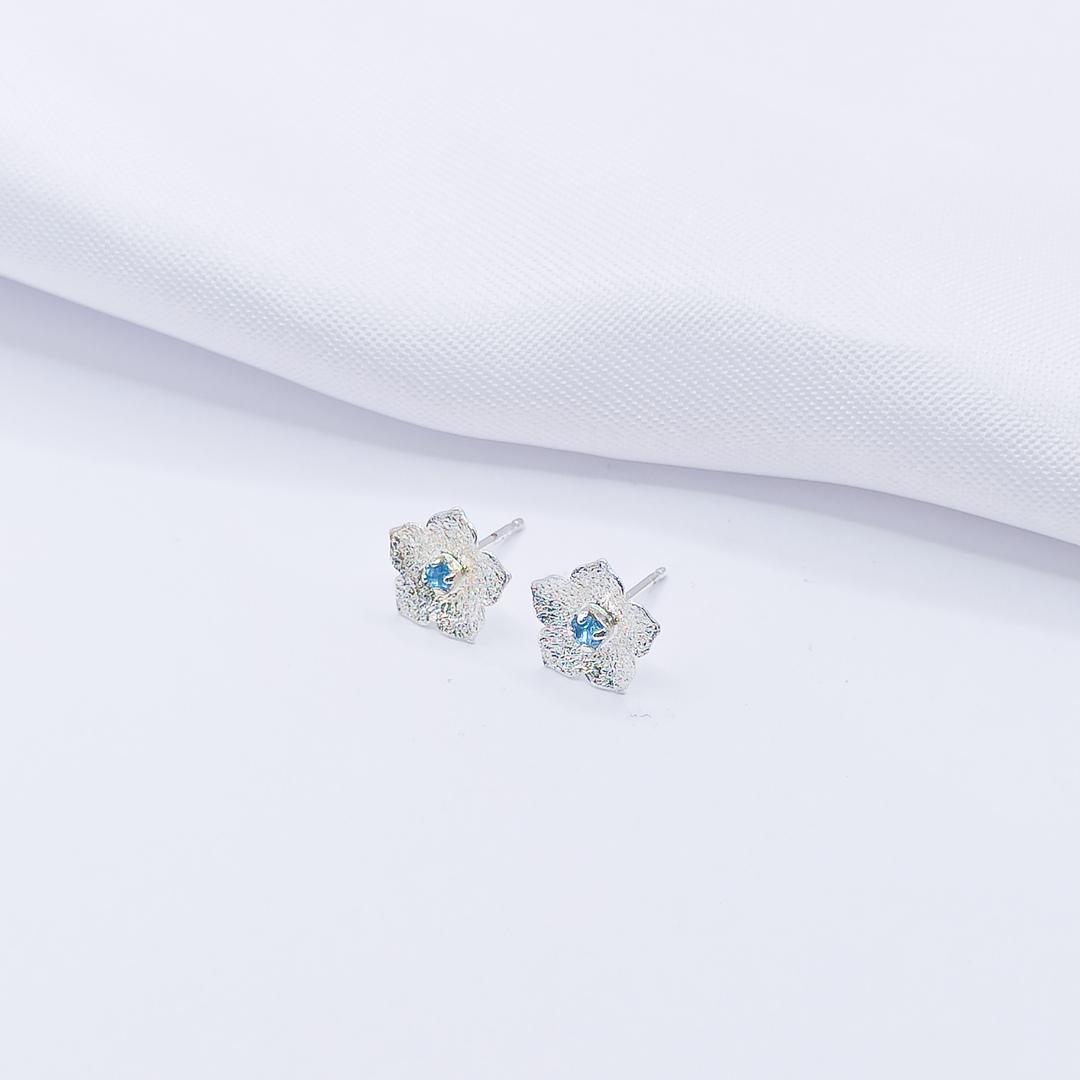 BRINCO PRATA FLOR COM PONTO DE LUZ AZUL CLARO P